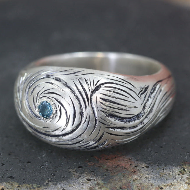 Silver ring with a blue stone on a dark surface