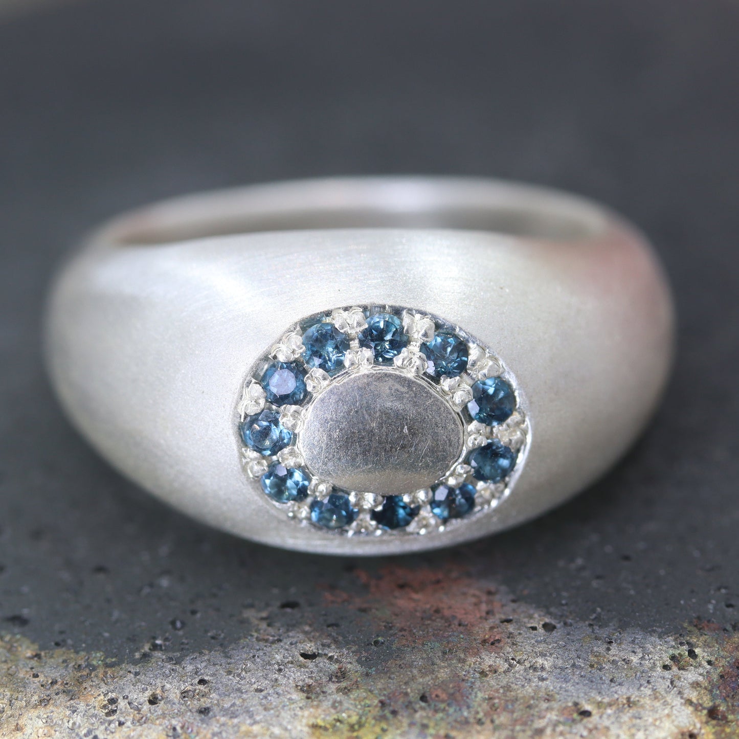 Silver ring with blue gemstones on a textured surface