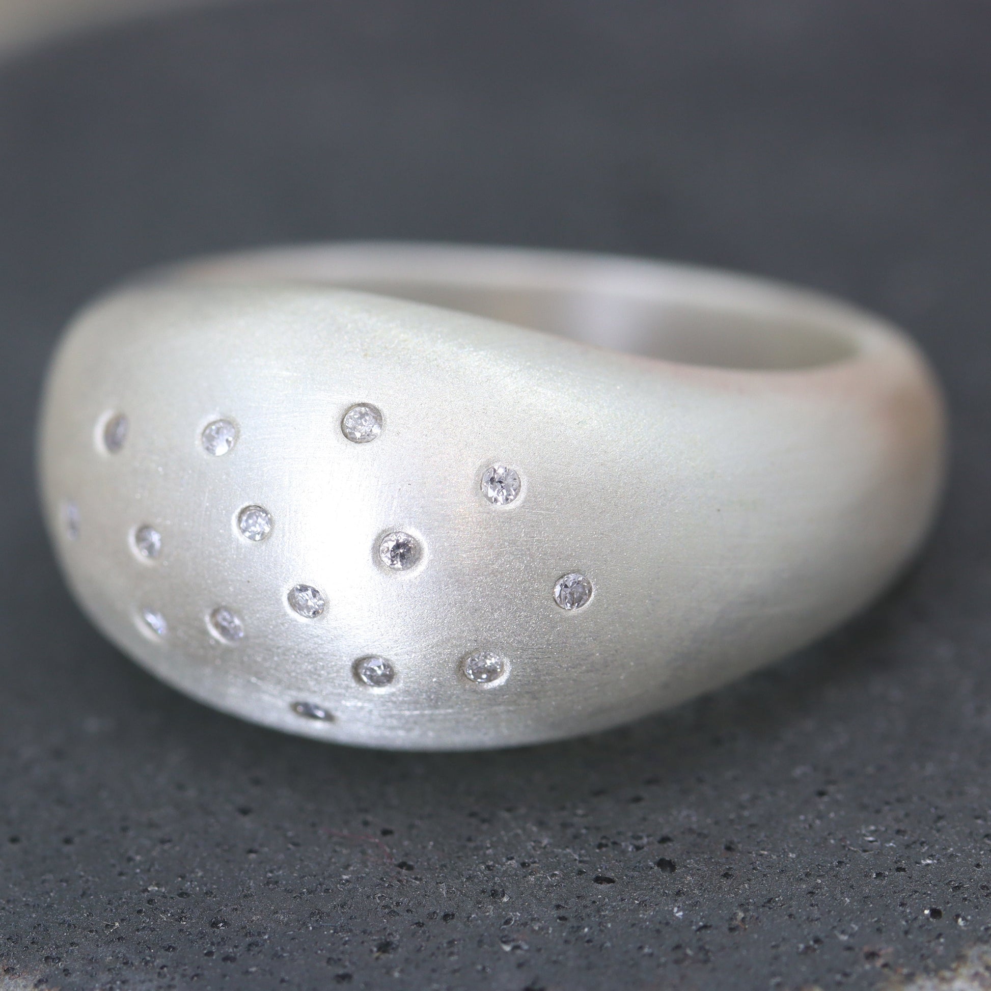 Silver ring with embedded stones on a textured surface