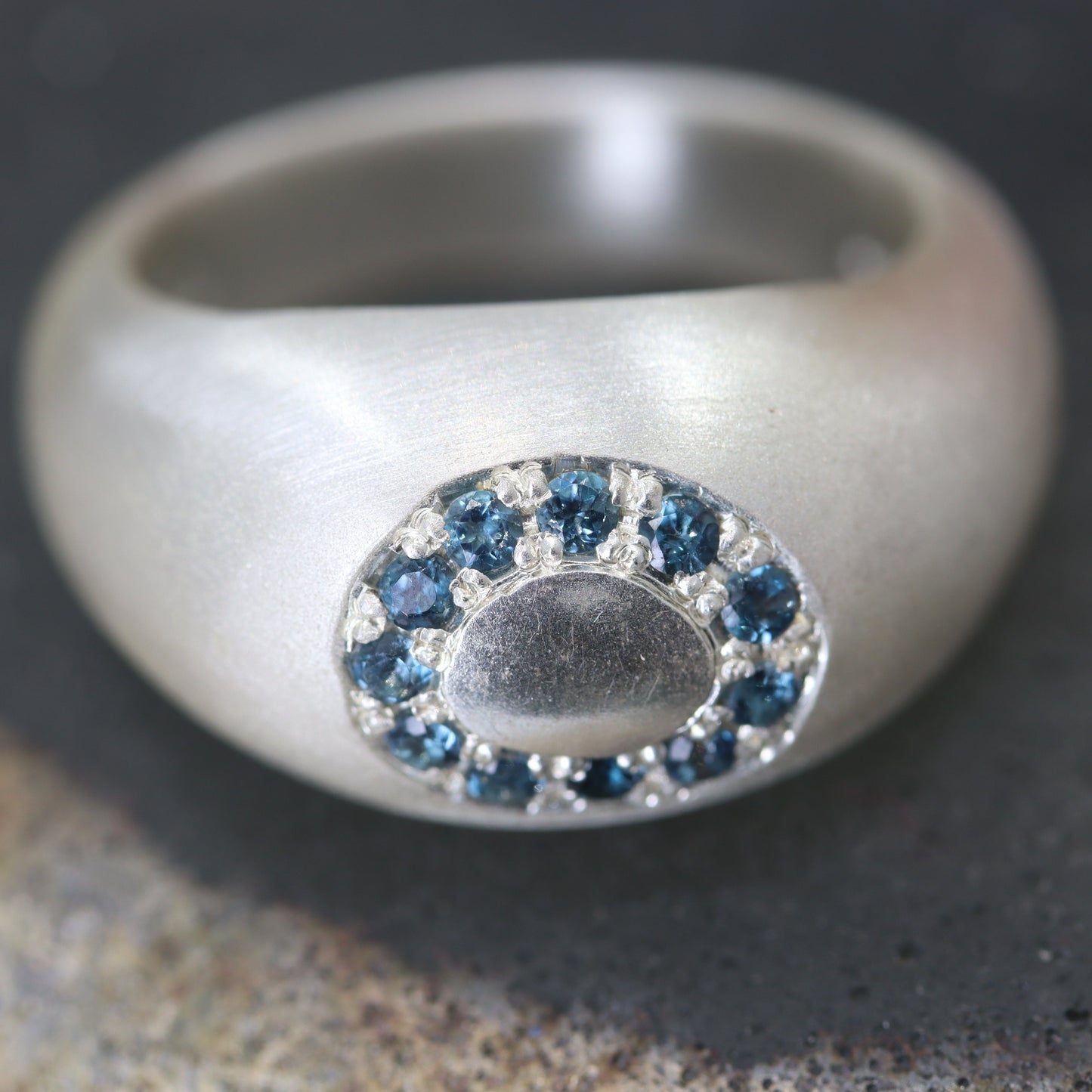 Silver ring with blue gemstones on a textured surface