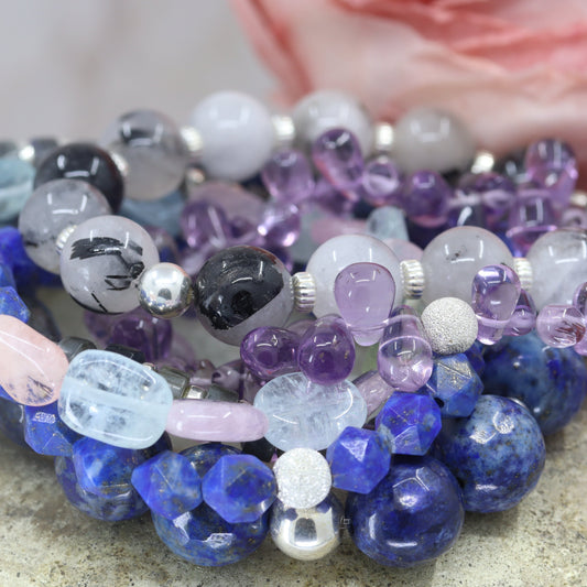 Stack of multicolored beaded bracelets on a textured surface with a blurred background