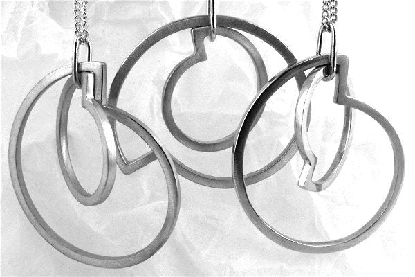 Three Art Deco silver necklaces displayed